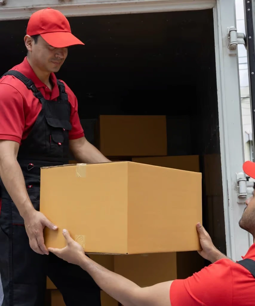 Zwei FlexiTrans-Mitarbeiter übergeben einen Umzugskarton am Transporter